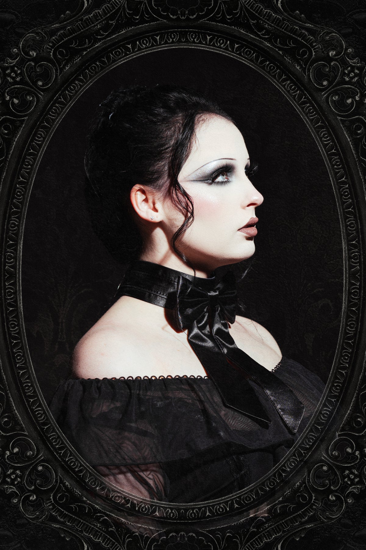A gothic portrait of a woman in profile wearing a black off-the-shoulder dress with a large black bow choker, set within an ornate oval frame against a dark background.