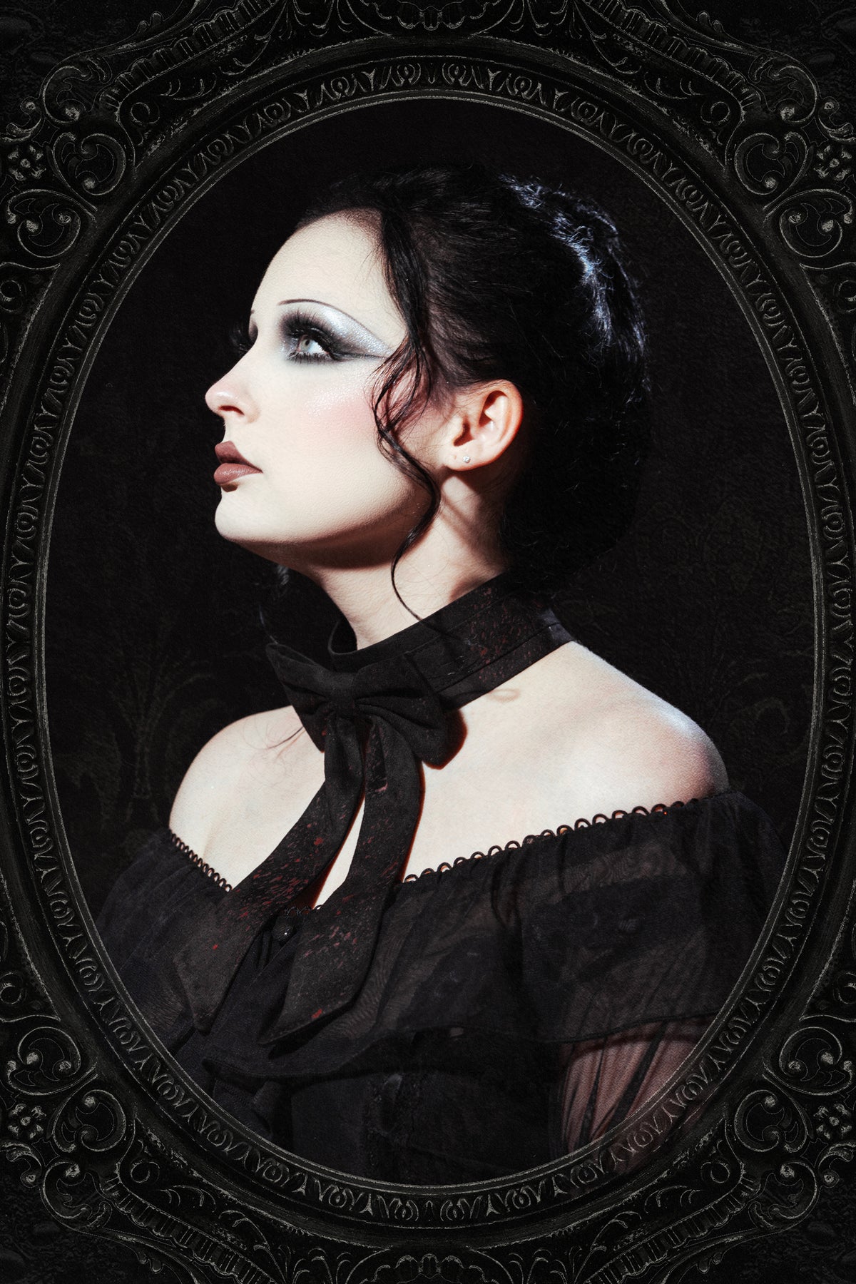 a woman photographed from the side in an ornate framed black background with a black bow tie choker that has red splattered on it