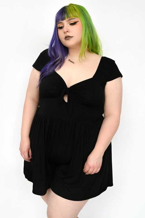 This all black romper features a tie front with small keyhole, and flattering flowing shorts. Smocked back for the perfect comfy fit. The tie front unties, but the keyhole is sewn shut, so the top does not open fully at the tie
