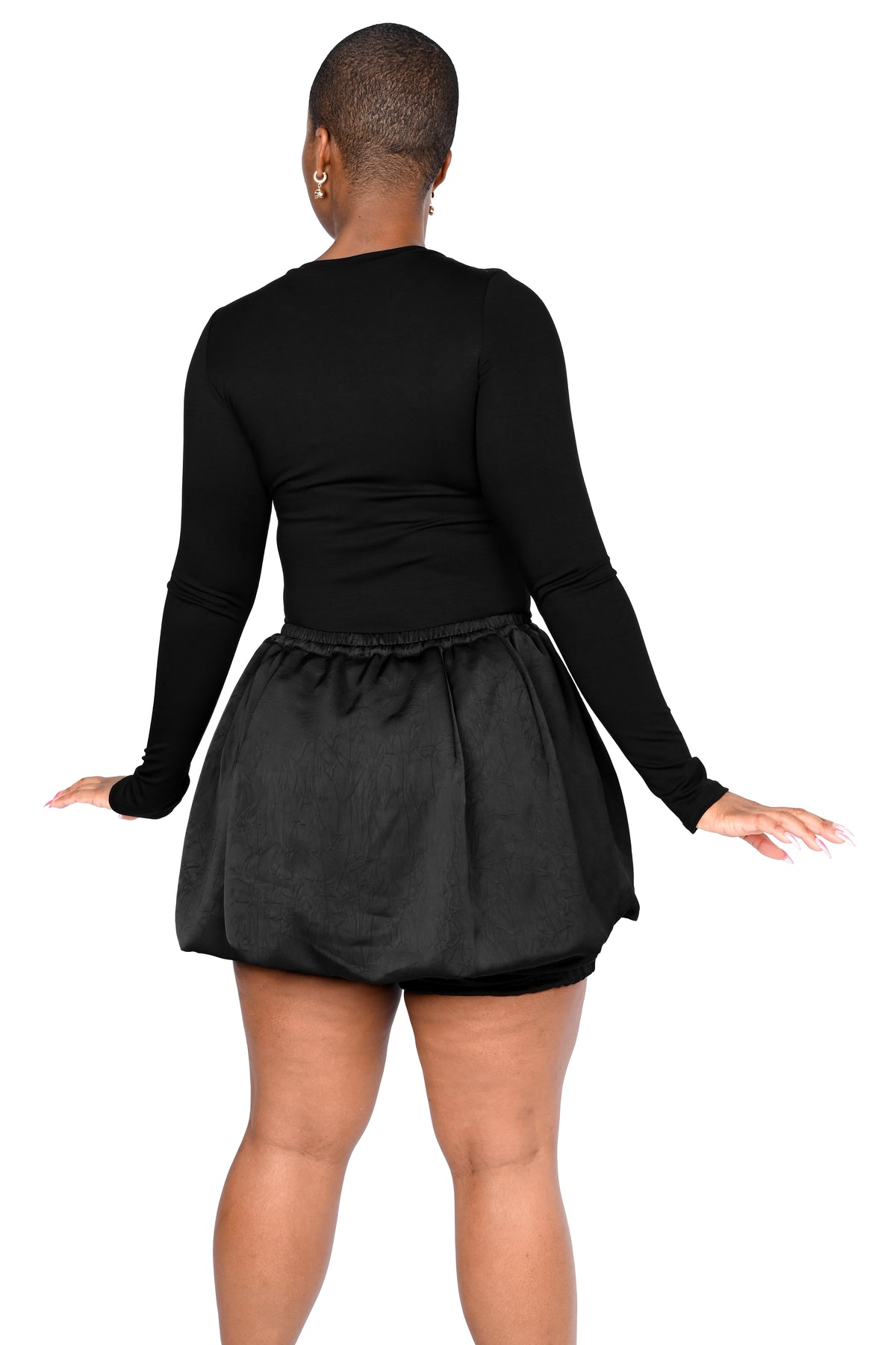 A person shown from the back wearing a black long-sleeve top and a black flared skirt against a plain white background.