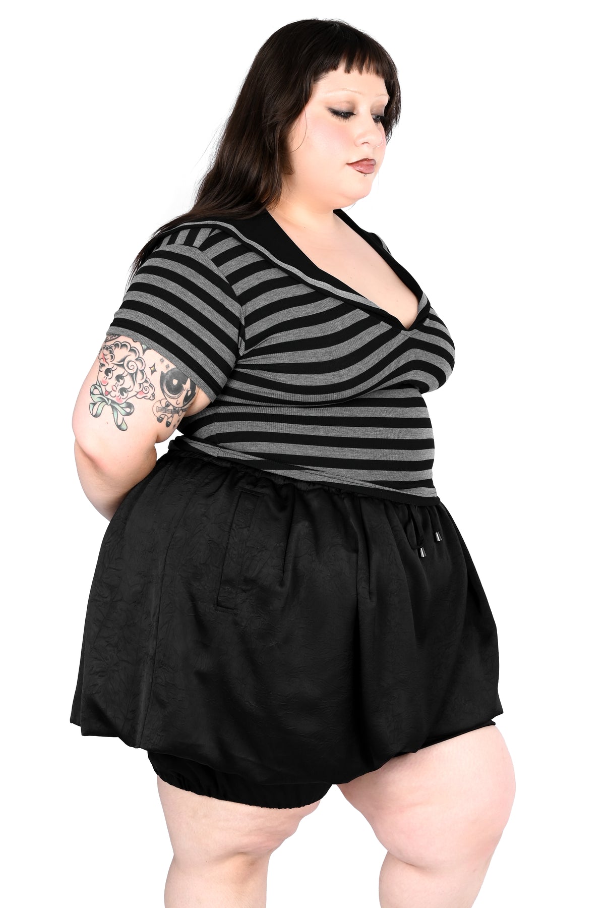 A plus-size model wearing a black and gray striped short-sleeve top and black shorts, shown from the waist up against a plain white background.