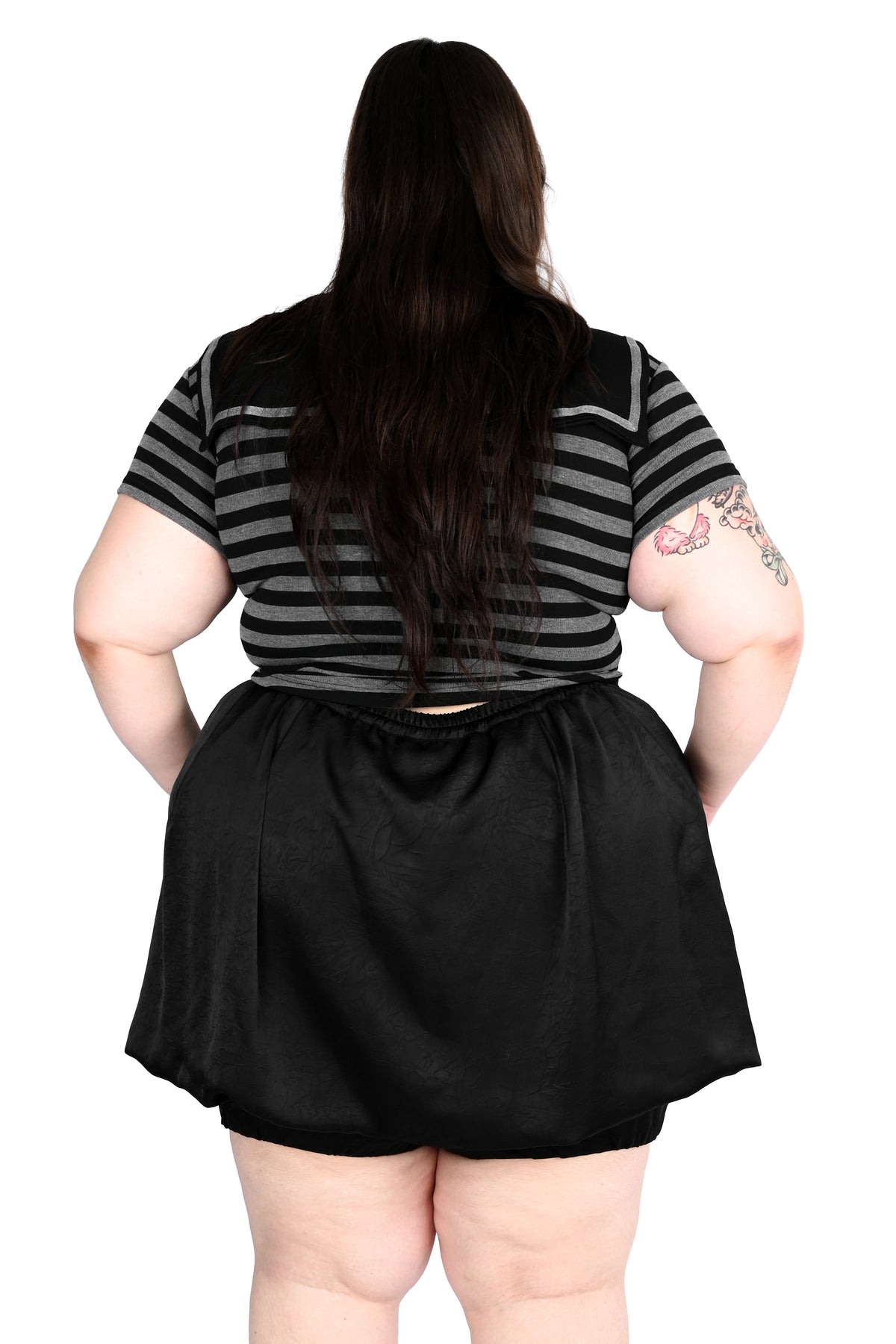 A person shown from the back wearing a black and gray striped short-sleeve top and a black skirt, against a plain white background.