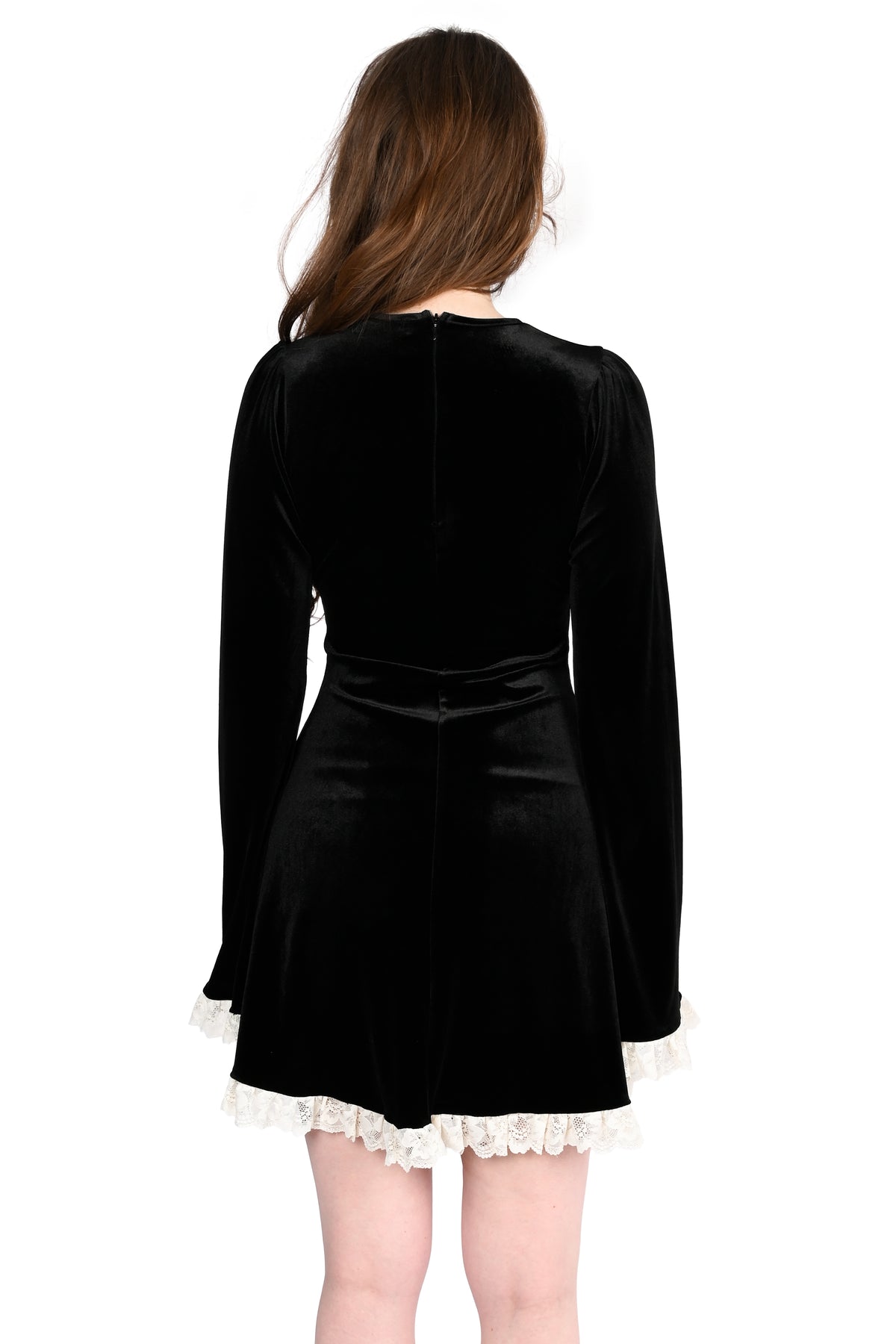 A woman viewed from the back wearing a black velvet long-sleeve dress with white lace trim at the hem and cuffs, against a plain white background.