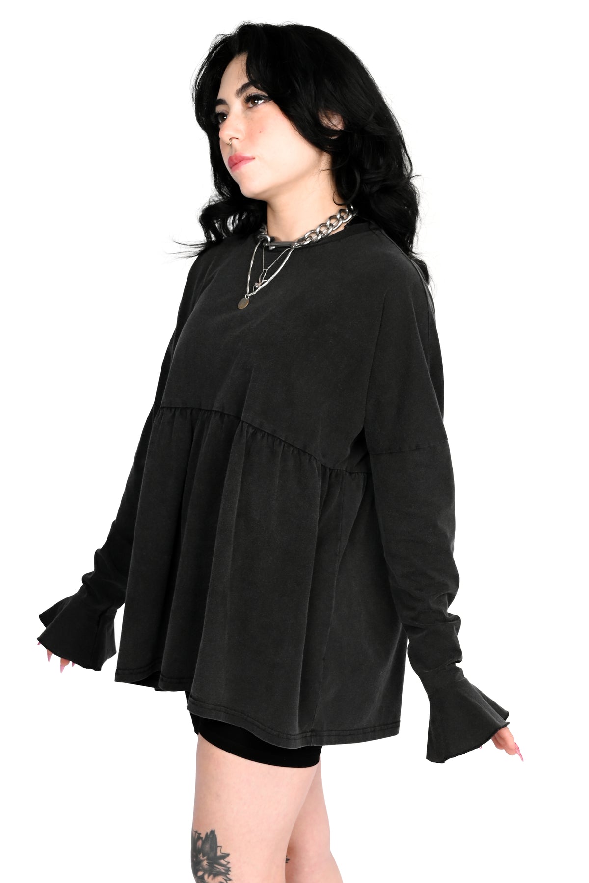 A woman modeling a black long-sleeve tiered tunic top with flared cuffs, shown against a plain white background.