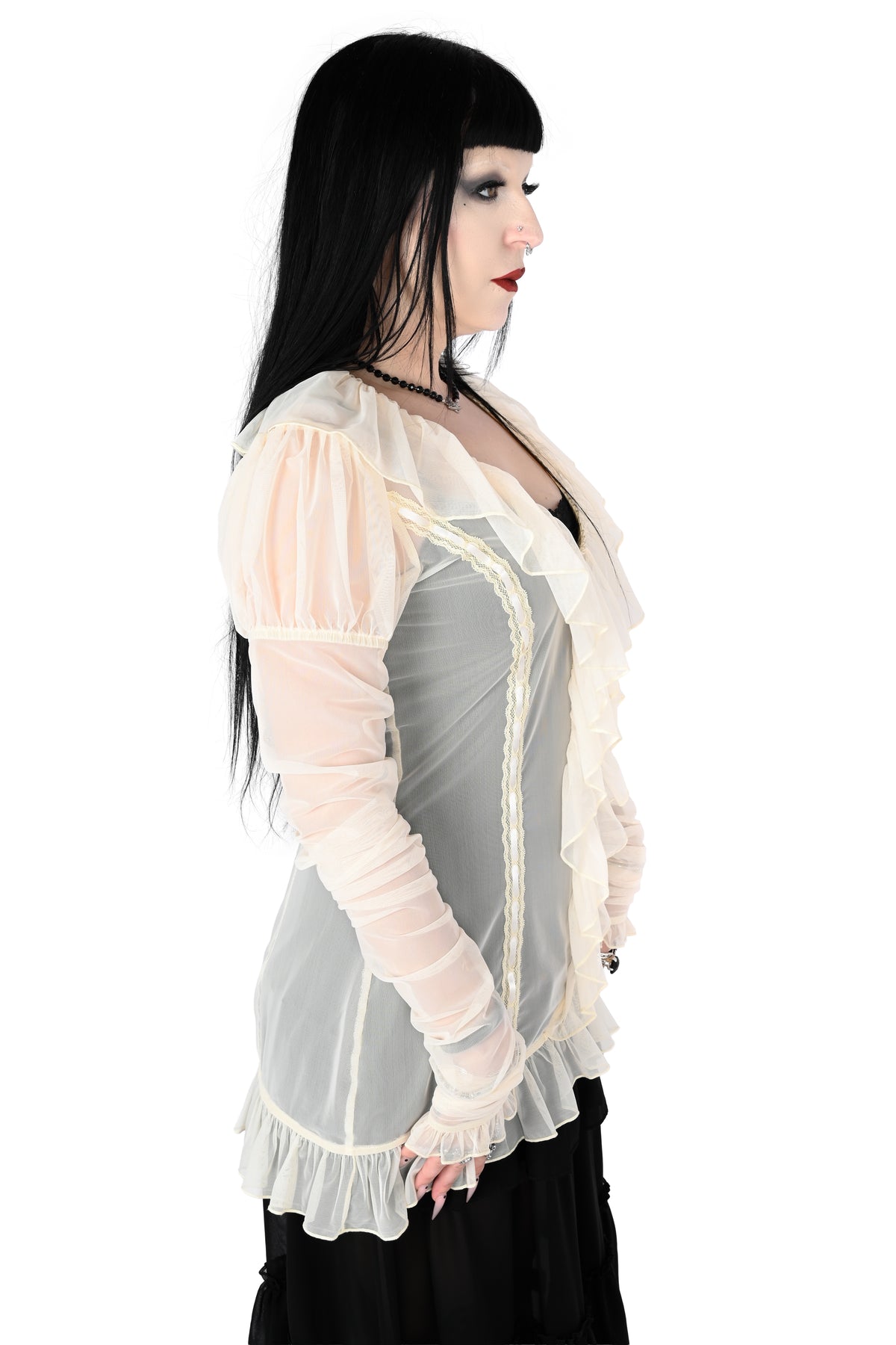 side view of a model wearing a cream sheer ruffle top with satin lace details in size xs