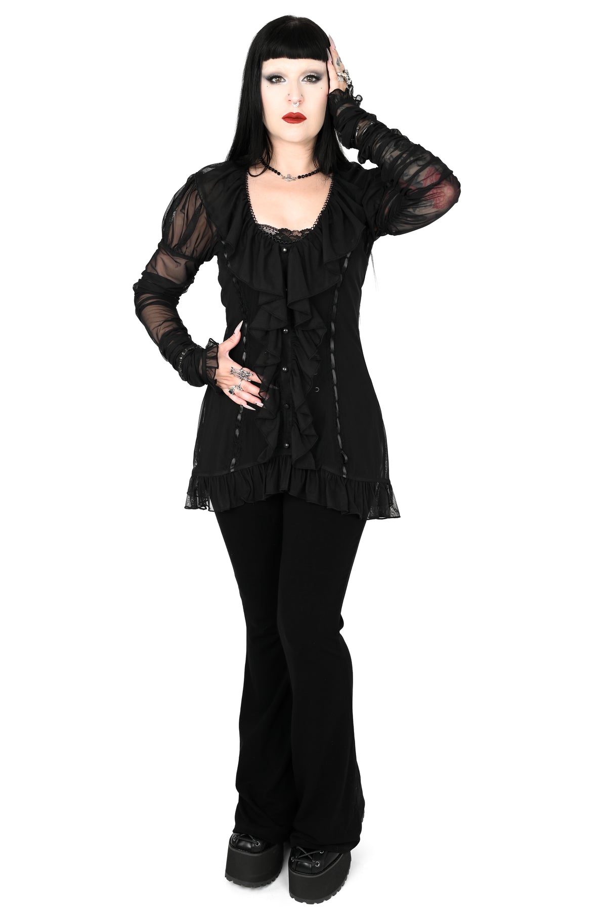 model wearing a black sheer ruffle top with satin lace details in size xs with one hand on her head
