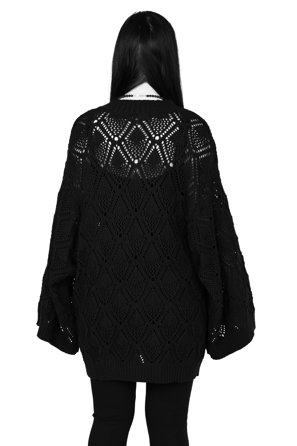 A person shown from the back wearing an oversized black open-knit sweater with a geometric lattice pattern across the upper back and long balloon sleeves, paired with black leggings against a plain white background.