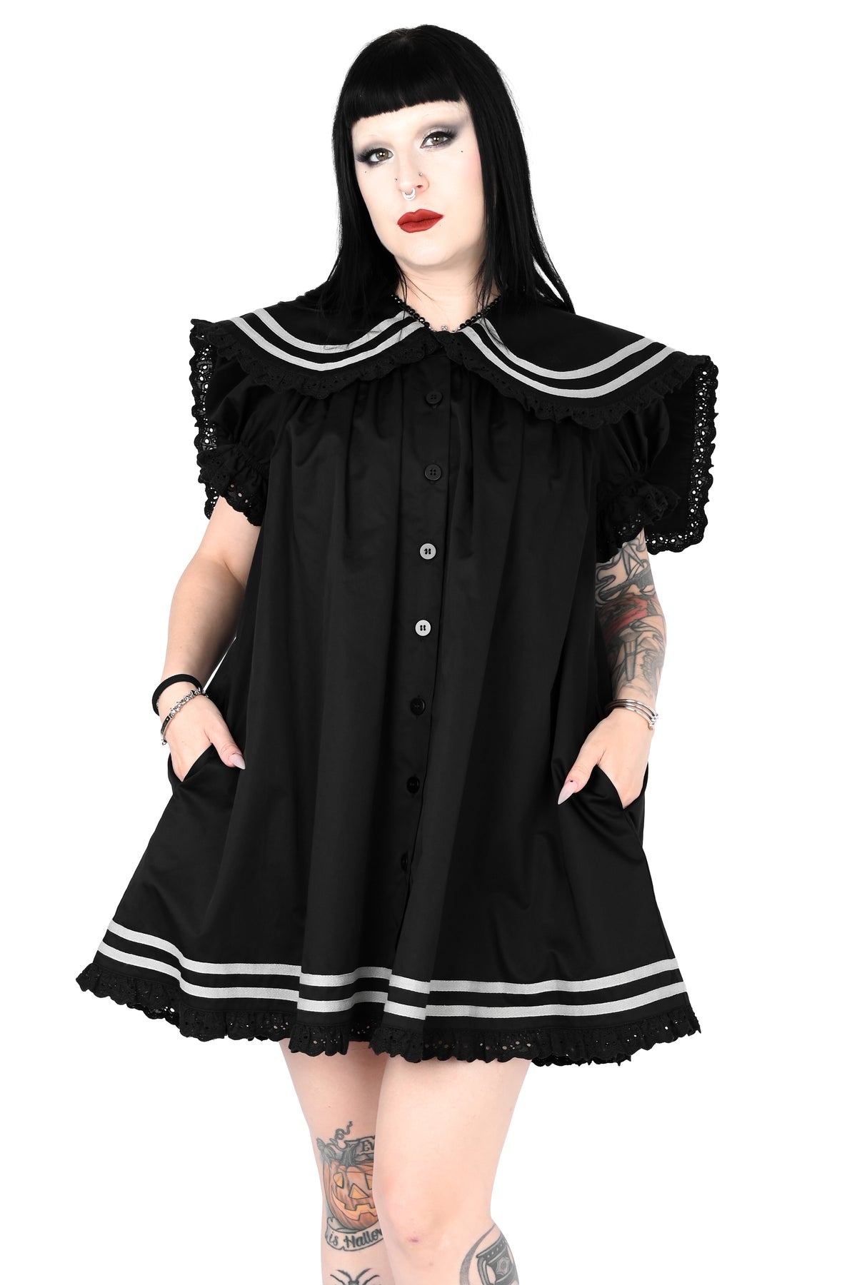 model wearing a black sailor dress with off-white stripe detailing and lace trim in size xs, posing with both hands in the pockets