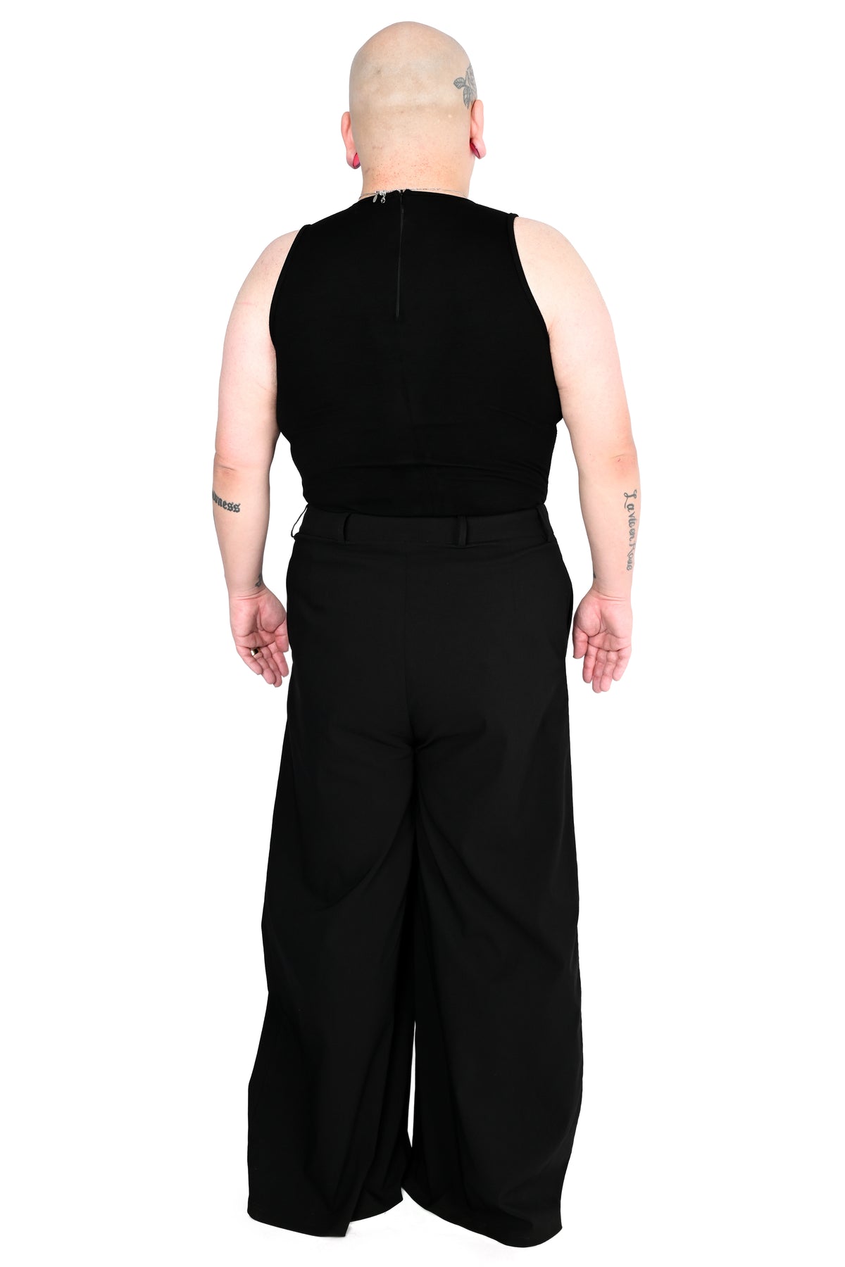 back view of a model wearing black high waisted wide leg pants with a sleeveless mock neck top in size 2xl