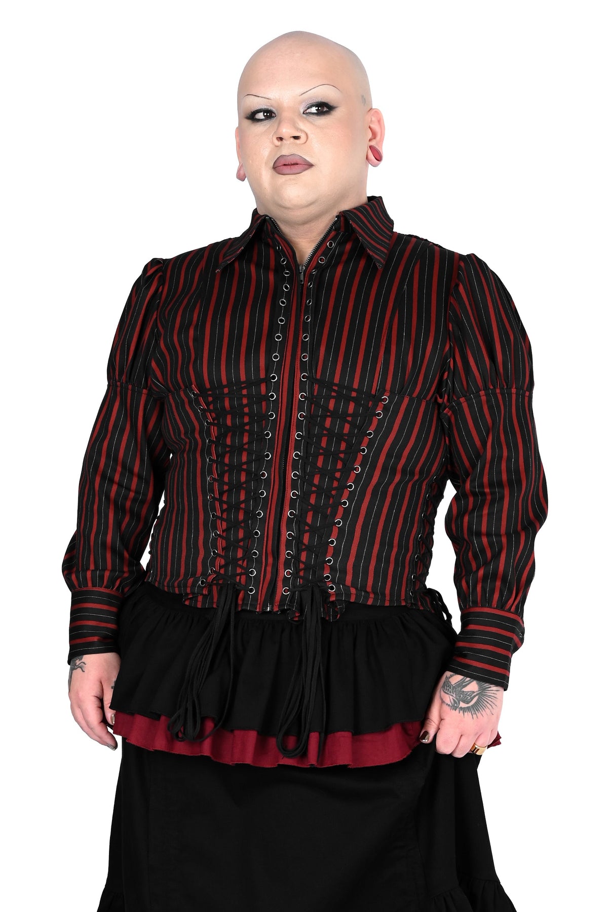 A person modeling a victorian-style jacket consisting of a black and red vertically striped long-sleeve blouse with lace-up front detailing, tiered black skirt with red ruffle accents, against a plain white background.