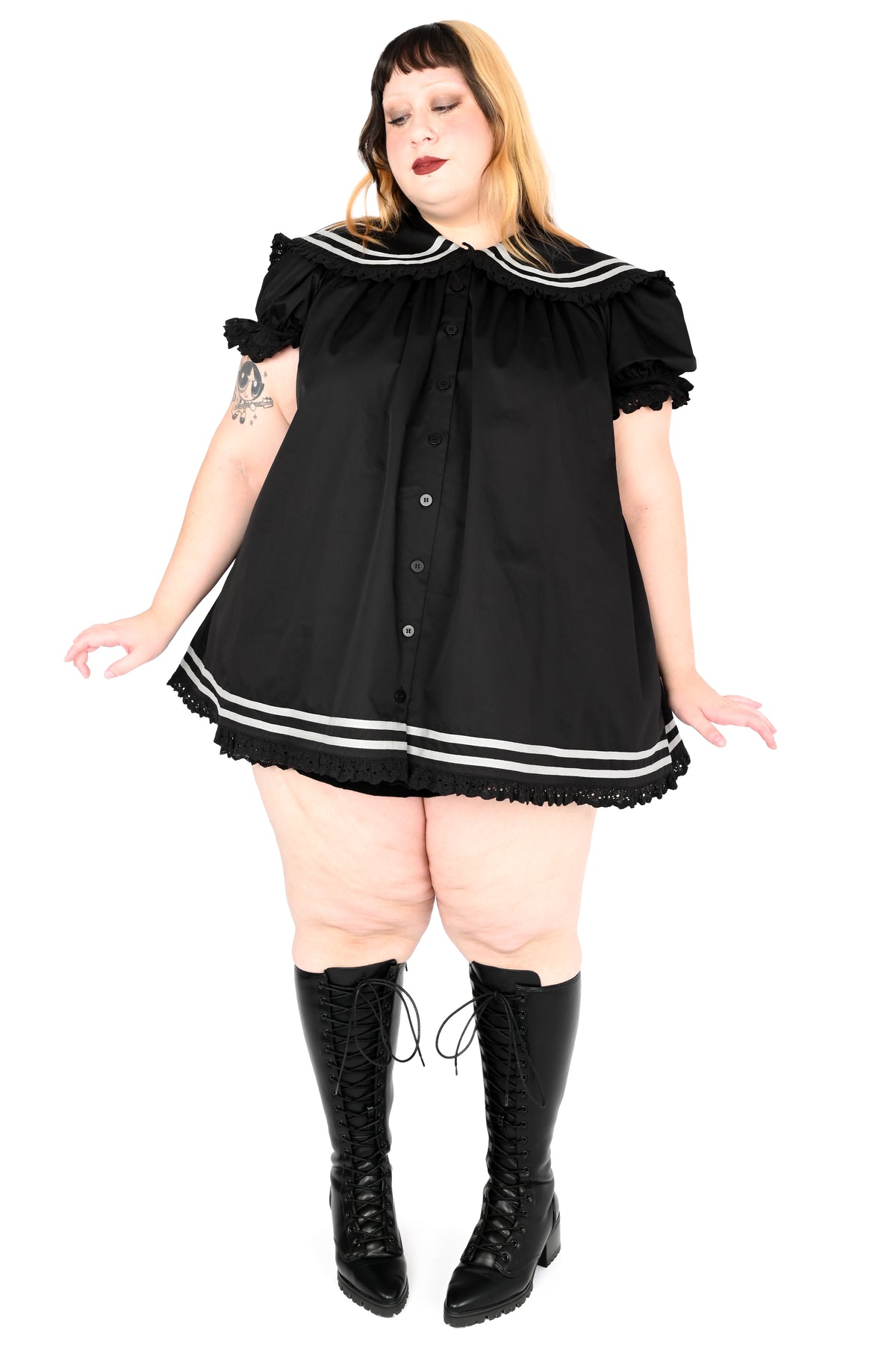 model wearing a black sailor dress with off-white stripe detailing and lace trim in size 2xl, paired with pointed toe lace up boots