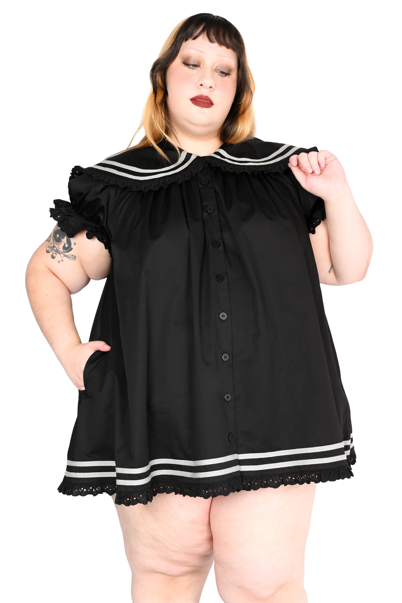 model wearing a black sailor dress with off-white stripe detailing and lace trim in size 2xl
