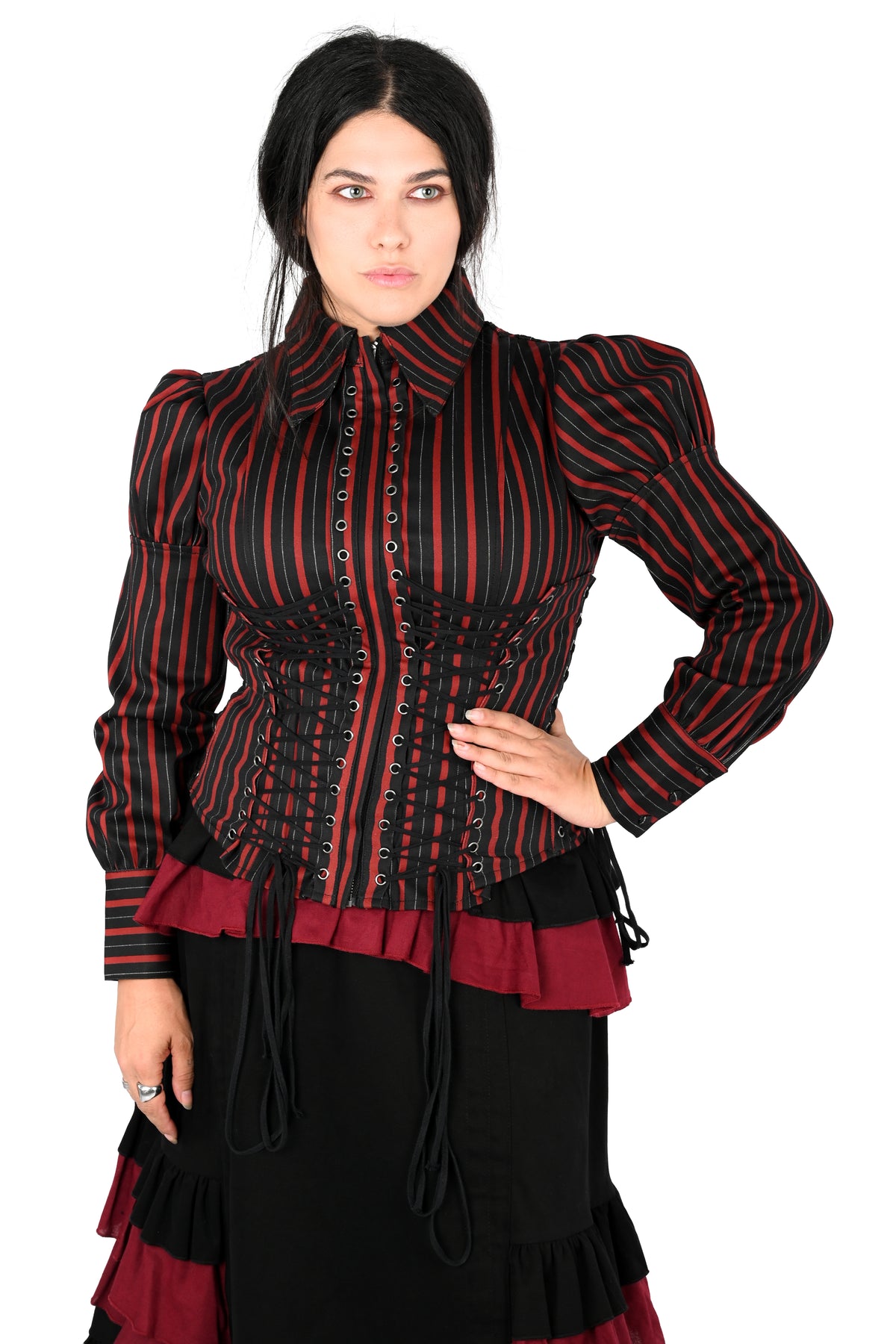 A woman modeling a Victorian-style corset jacket with red and black vertical stripes, black lace-up front.  paired with a black and burgundy tiered skirt against a white background.