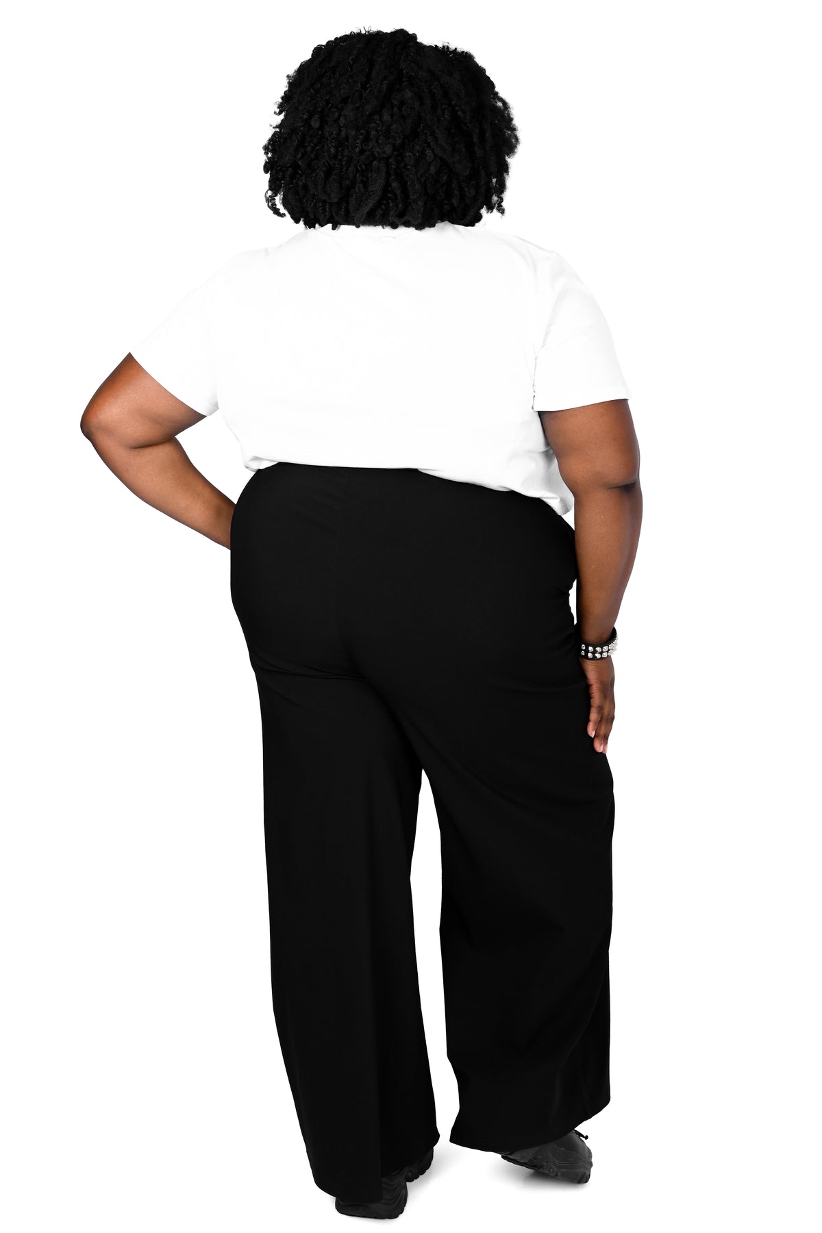 back view of a model wearing black high waisted wide leg pants with a white tee in size 3xl