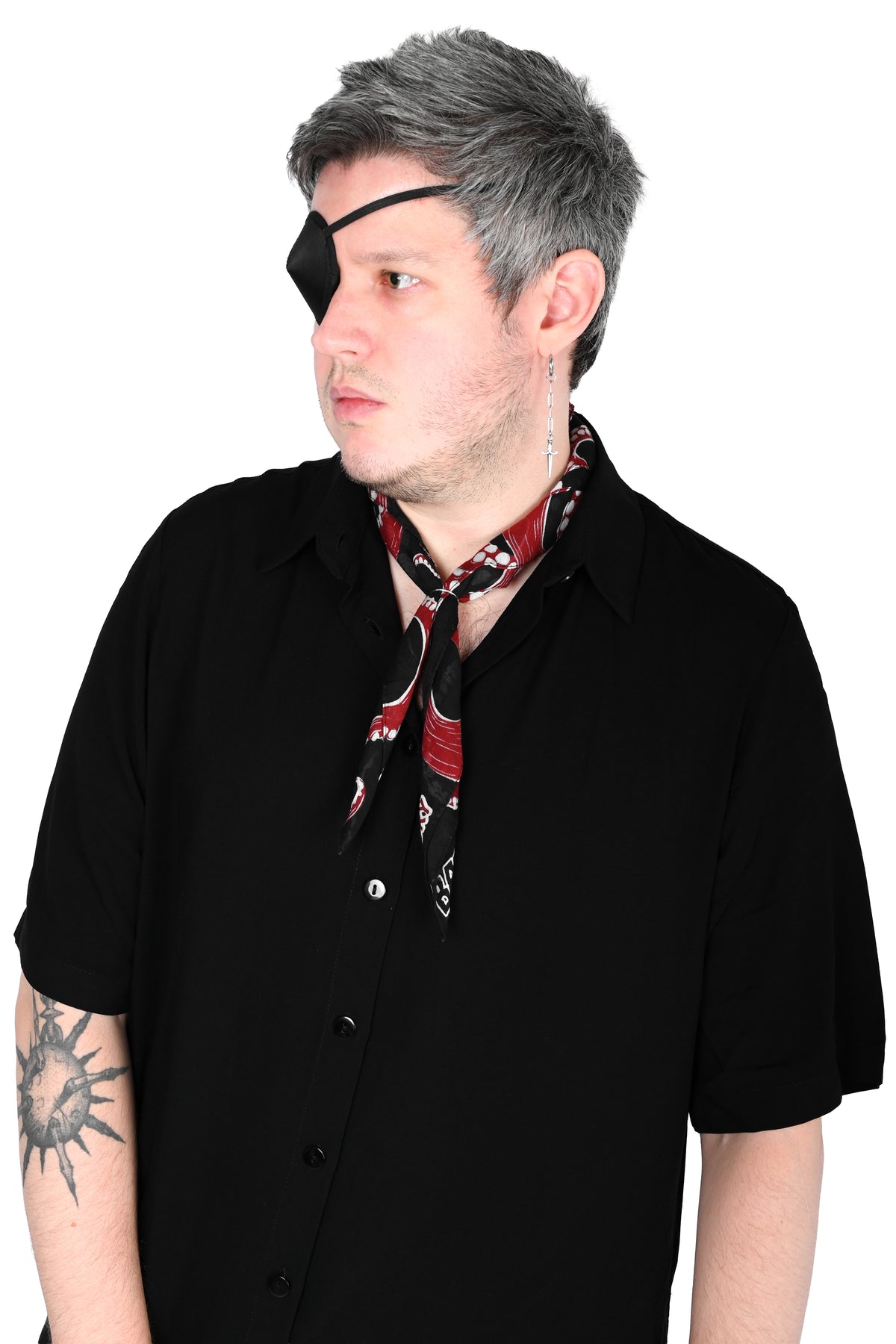 A man wearing a black pirate eye patch, a black short-sleeve button-up shirt. He is wearing the Thar Be Monsters patterned neck scarf tied around his neck, shown against a plain white background.