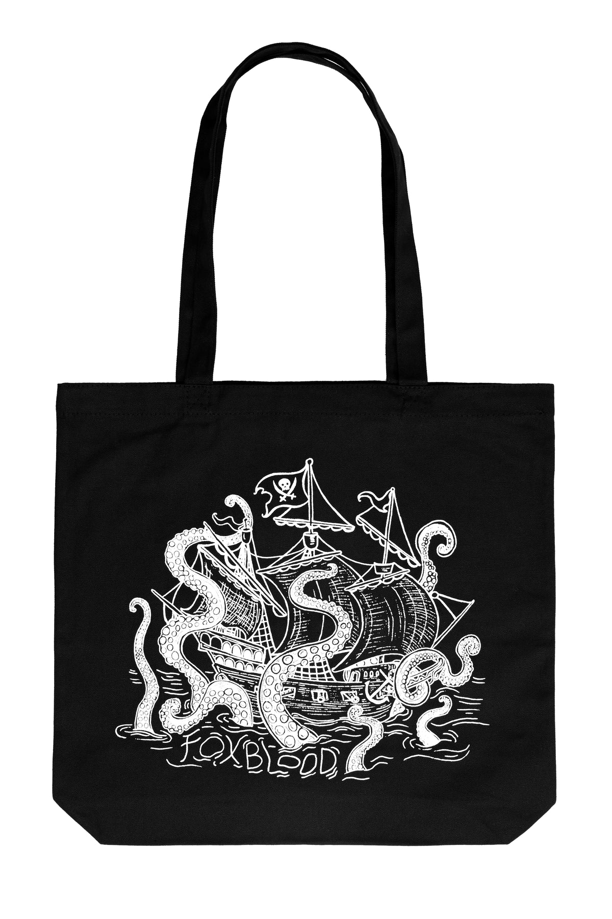 A flatlay of a black canvas tote bag with black handles, featuring a white line art graphic of a pirate ship being swallowed by a giant sea monster, with the text 'Foxblood' written /below in the ocean water lines. shot on a white background
