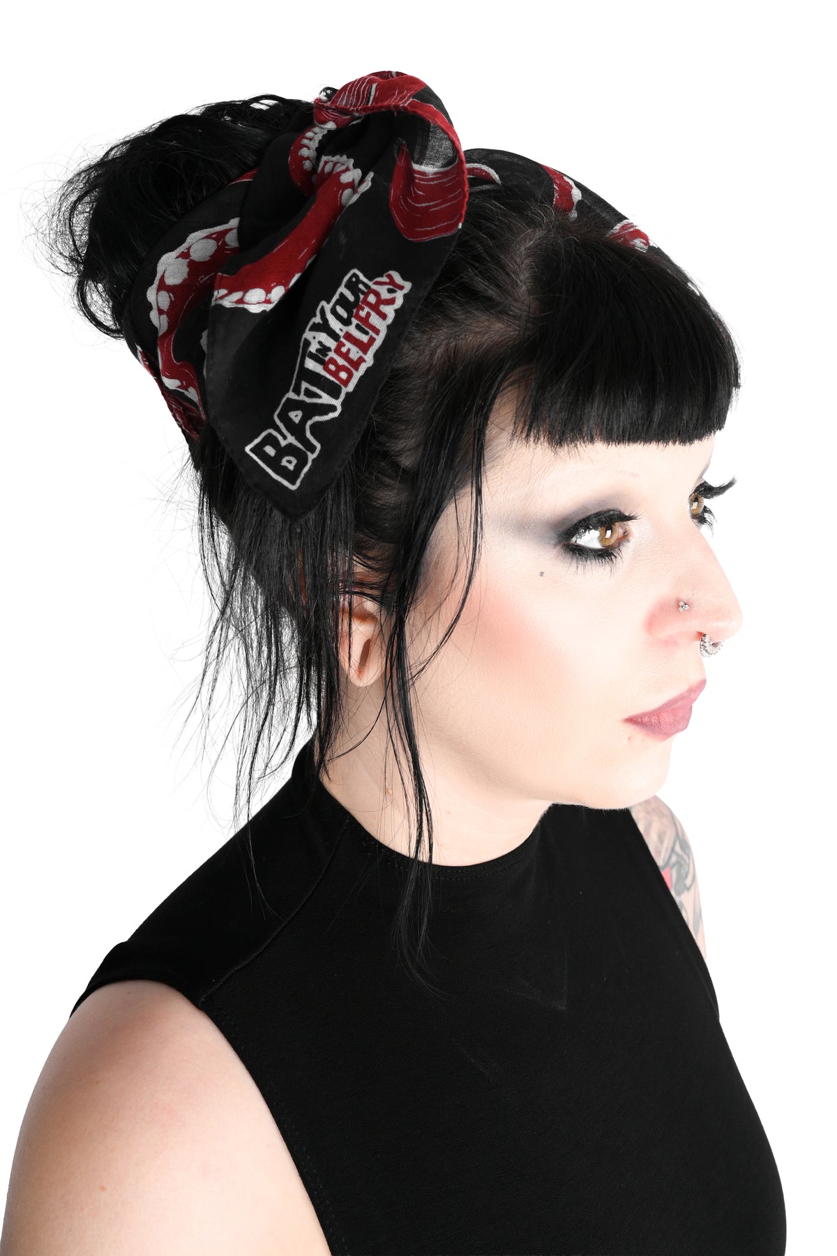 A front facing side view of a model dressed in all black wearing the thar be monsters scarf wrapped around her head. The scarf is black with red and white tentacles all over.  Shot on a white background.