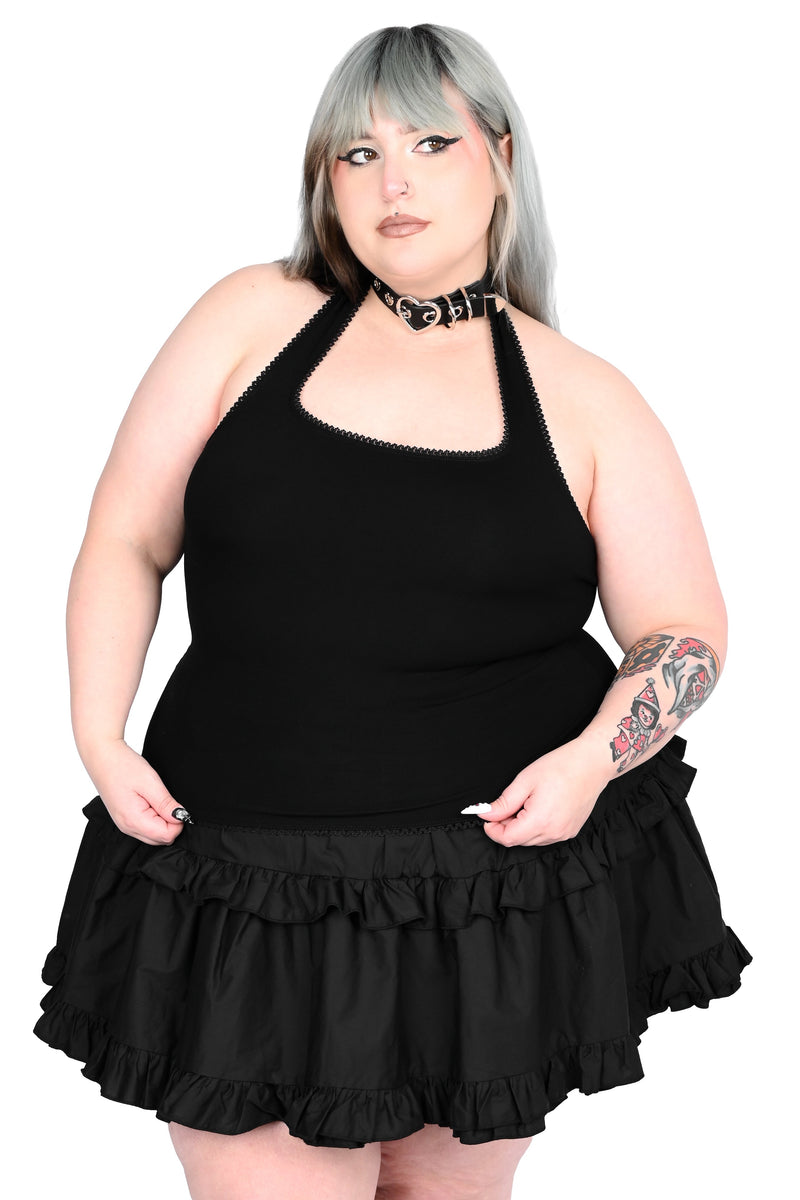 Person wearing a black halter top with ruffled skirt on a white background