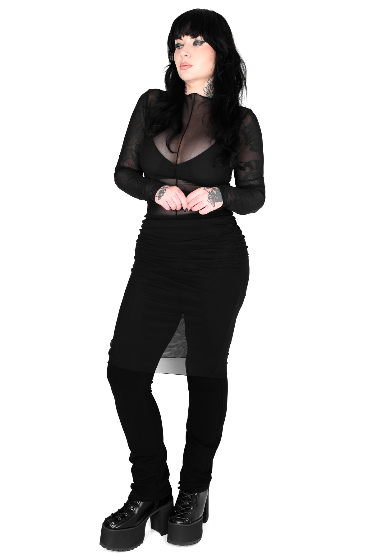 model wearing a black mesh long sleeve top with black pants that have a mesh skirt attached