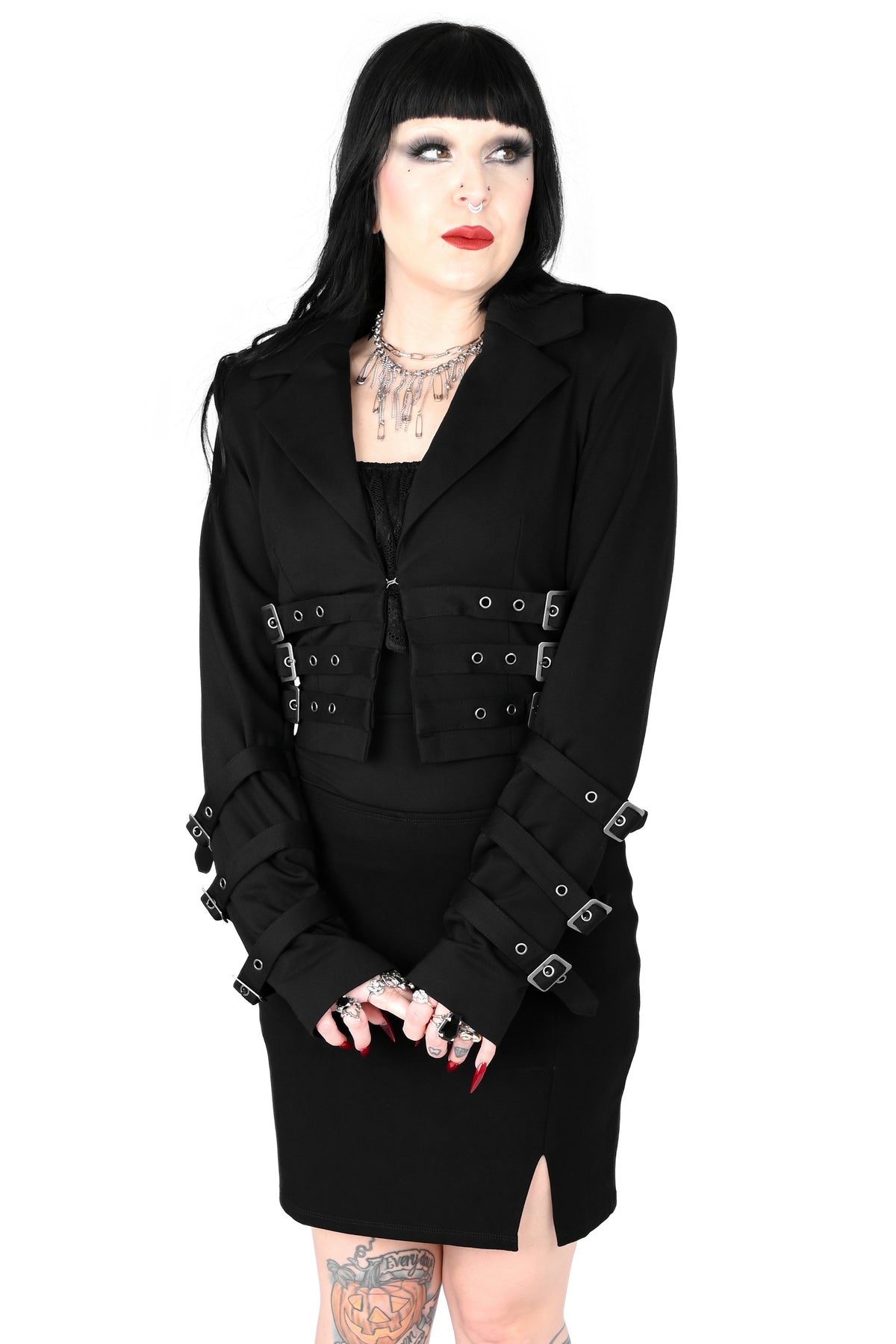 Black blazer with buckle straps on the front and sleeves, and shoulder pads.