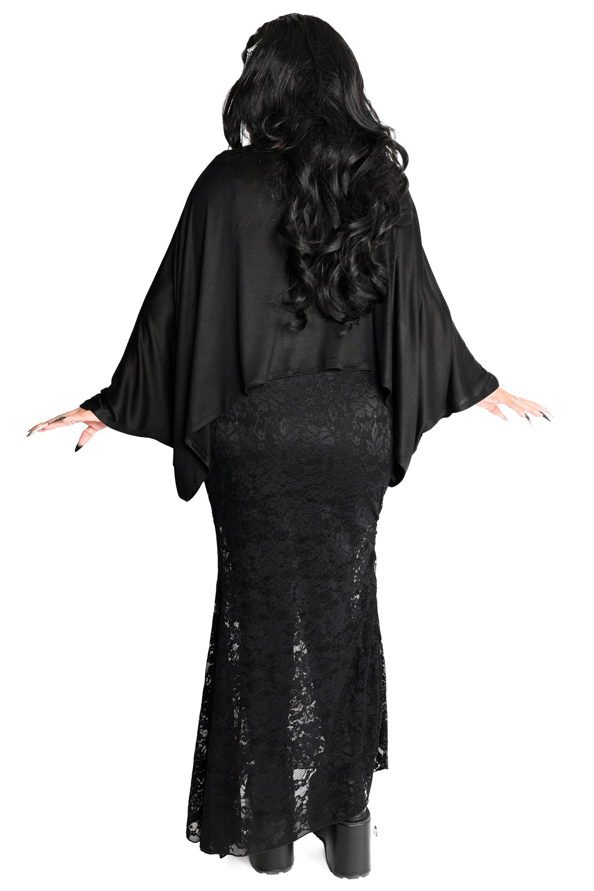 A woman shown from the back wearing a black gothic-style outfit with draped cape top and a fitted lace skirt, photographed against a plain white background.