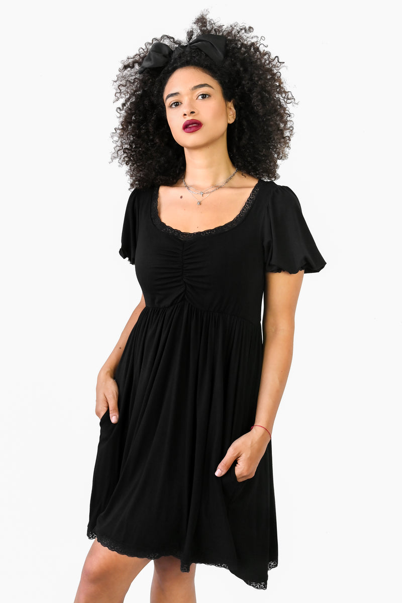above the knee black dress with pockets and lace trim on cuff sleeve, neckline and bottom hem  