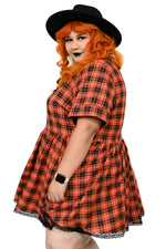This orange plaid swing dress has a pointed collar with lace trim, and the same trim on the bottom hem. Under the collar there is an adjustable ribbon