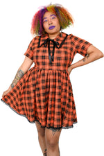 This orange plaid swing dress has a pointed collar with lace trim, and the same trim on the bottom hem. Under the collar there is an adjustable ribbon