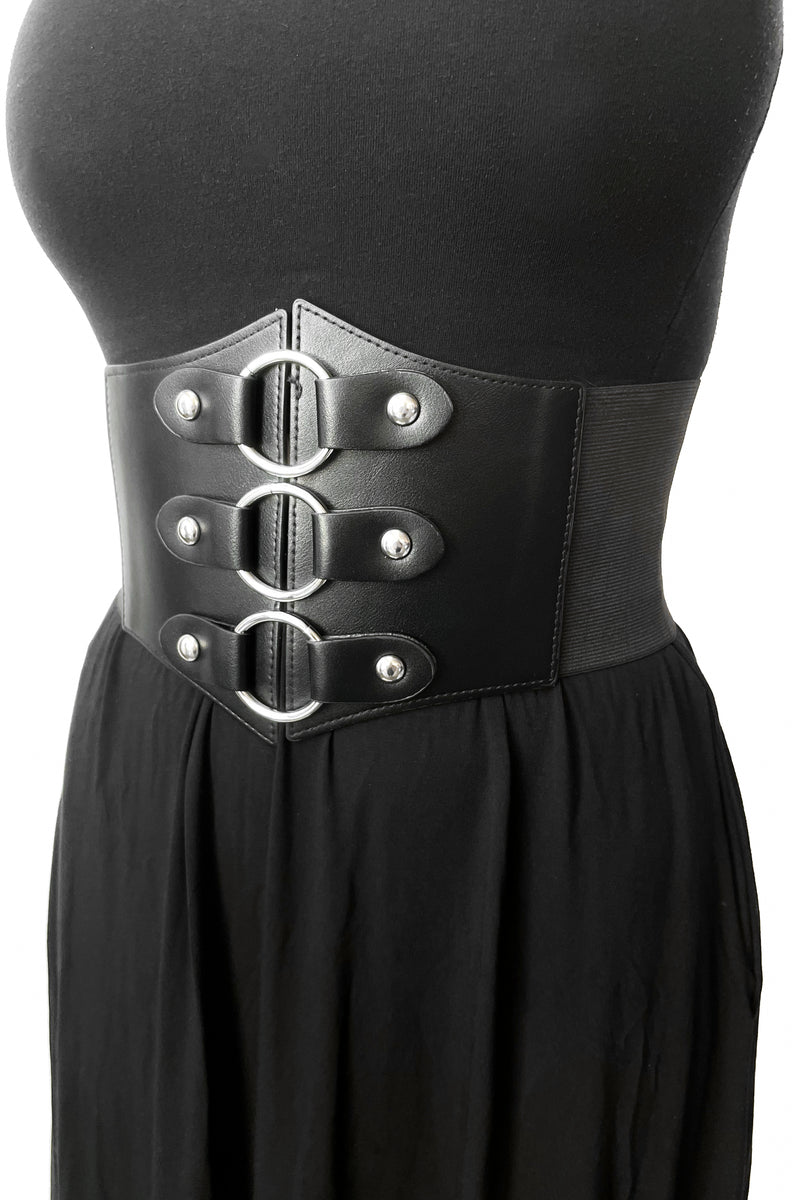 Black corset style belt with vegan leather front and elastic back. Front has 3 metal rings attached with a grommet to the belt.