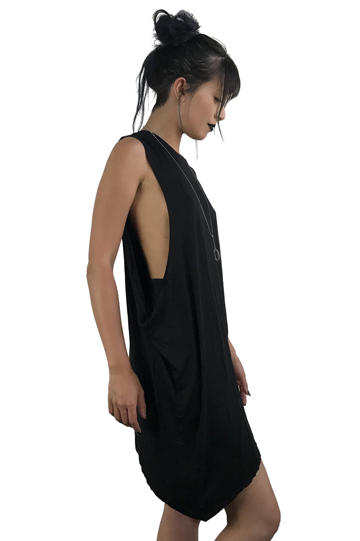 Side view of model wearing a black longline symmetrical tunic. It has a left sleeve and the right side is sleeveless